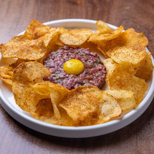 Beef tartare with a raw egg yolk in the center, surrounded by crispy potato chips.