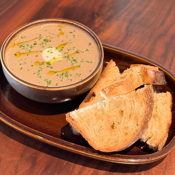 Creamy mushroom soup with chives, olive oil, and a dollop of cream, served with toasted bread.