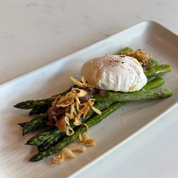 Grilled asparagus spears topped with a poached egg, caramelized onions, and crispy fried shallots.