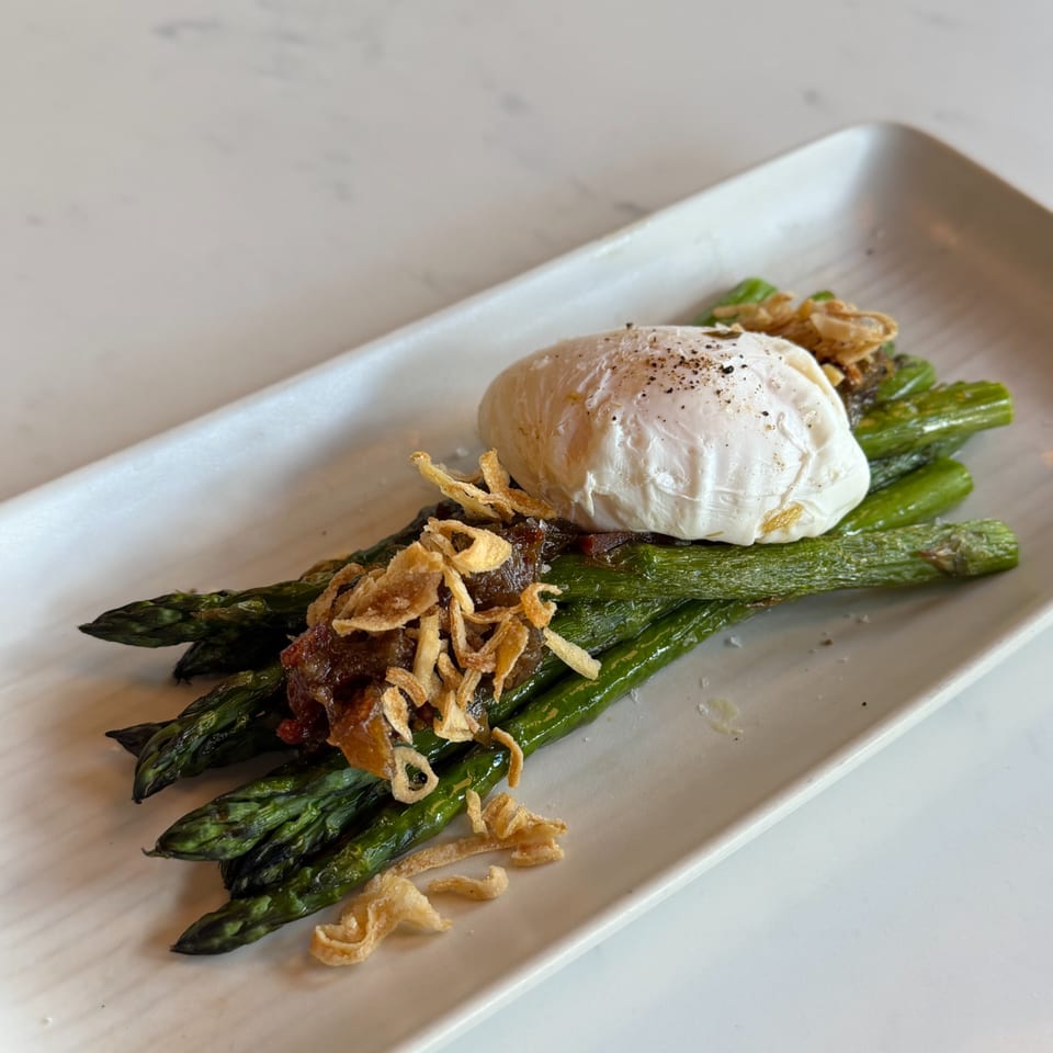 Grilled asparagus spears topped with a poached egg, caramelized onions, and crispy fried shallots.